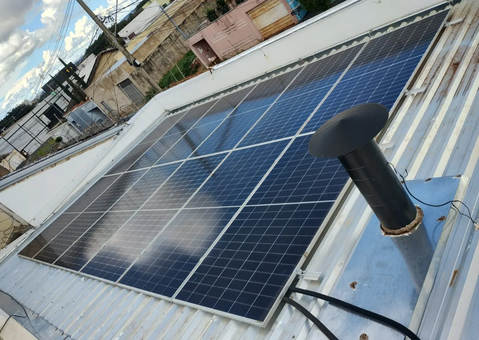Painéis solares instalados sobre cobertura metálica, ao lado de um exaustor