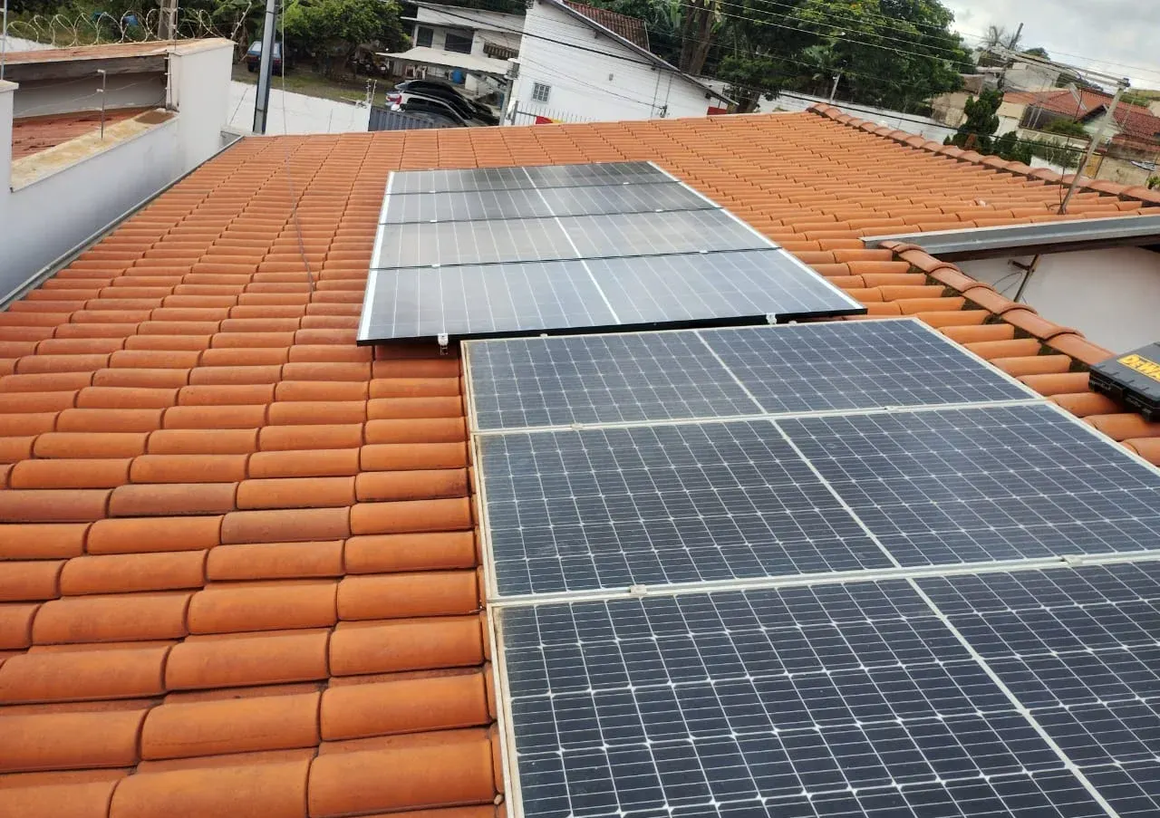 Dois conjuntos de painéis solares instalados em sequência sobre telhado cerâmico