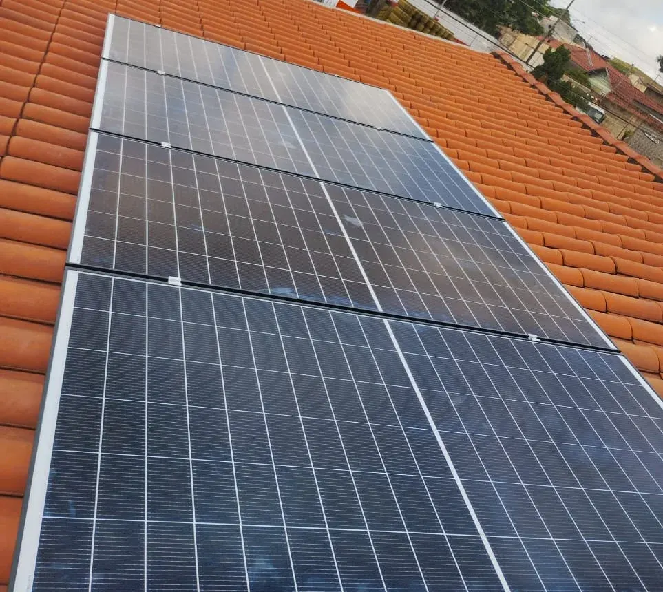 Painéis solares alinhados sobre telhado de telhas cerâmicas, vistos de perto