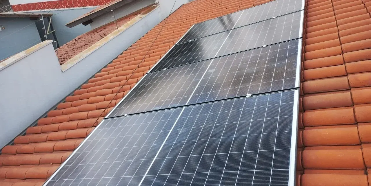 Oito painéis solares instalados sobre telhado residencial de telhas cerâmicas