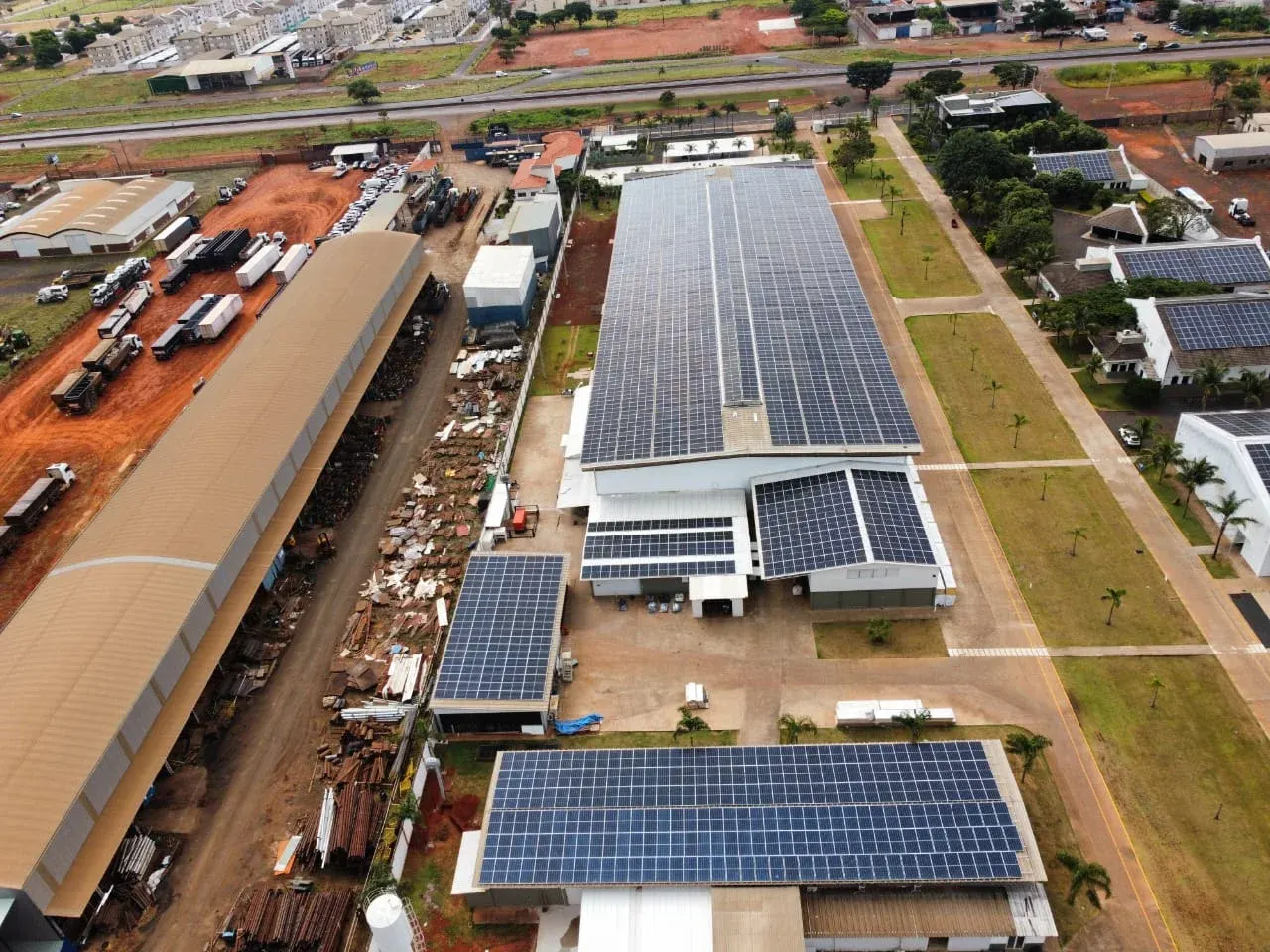 Galpão principal com o telhado inteiro coberto por módulos fotovoltaicos, visto de drone